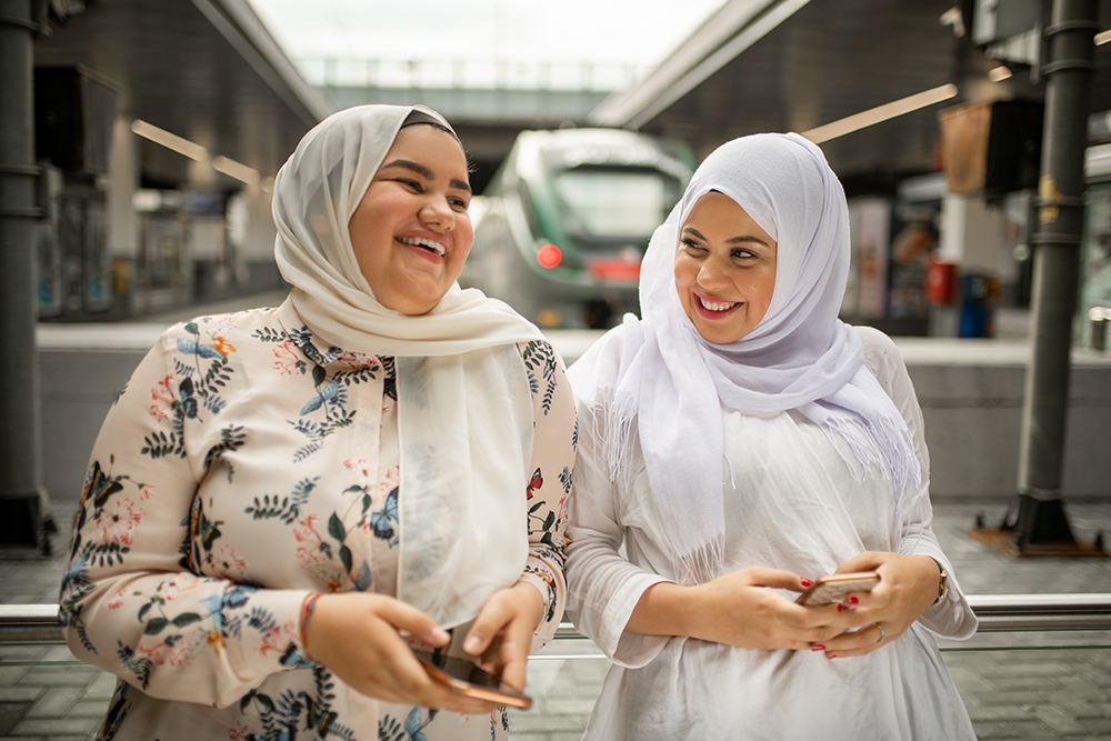 两个年轻的女人在火车站使用移动电话