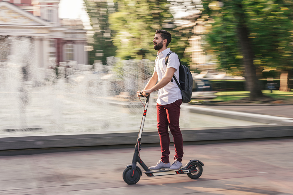 一个自信的年轻人在城市里骑着电动滑板车